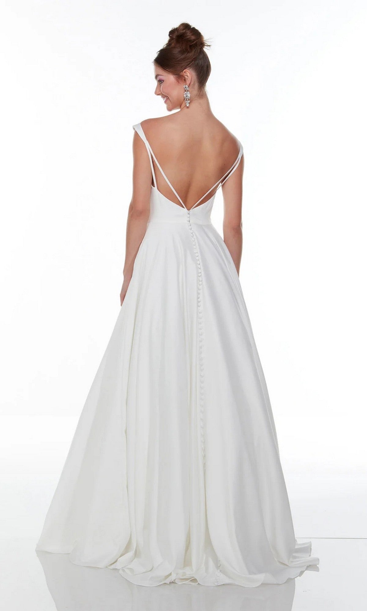 A woman models the Alyce 7053, a long white satin A-line gown with thin straps, backless design, floor-length skirt, and button details down the back, set against a plain white background.